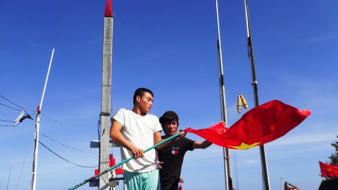 Ngư dân được cảnh sát biển tặng cờ Tổ quốc để thay cho những lá cờ đã cũ trên tàu - Ảnh: Lê Trung