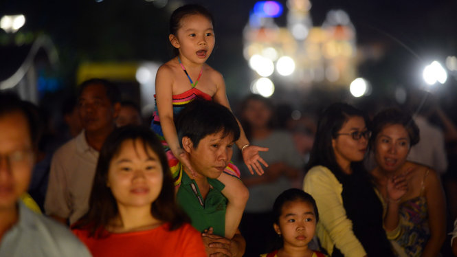 Một em nhỏ thích thú xem biểu diễn nghệ thuật đường phố - Ảnh: Quang Định