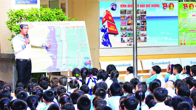 Thầy tổng phụ trách Đội Nguyễn Tất Bình hướng dẫn học trò xem triển lãm về biển đảo tại sân trường - Ảnh: C.K.