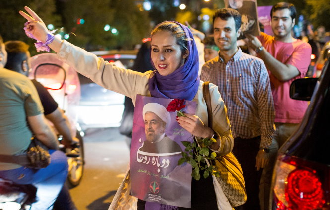 Cử tri ủng hộ ứng viên Hassan Rouhani mang hình ảnh ông trong cuộc tuần hành trên đường phố ở Tehran - Ảnh: Reuters