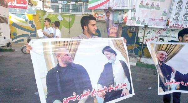 Người Iran mang tấm poster có hình cuộc trò chuyện giữa ông Raisi với Titlo - Ảnh: aawsat