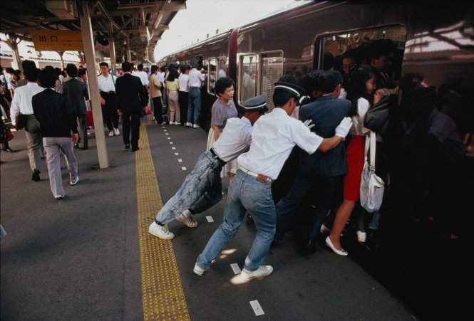 Nhân viên đường sắt ở Honshu, Tokyo, Nhật Bản ở Honshu dồn người đi làm lên một chuyến xe lửa đông đúc - Ảnh: Getty Images