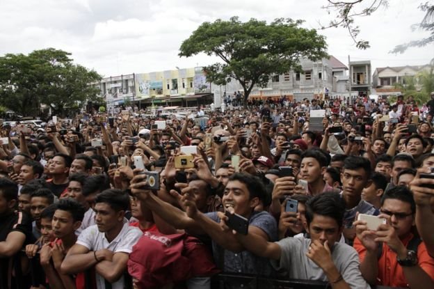 Đám đông dùng điện thoại di động quay cảnh đánh roi nơi công cộng ở Banda Aceh - Ảnh: AP