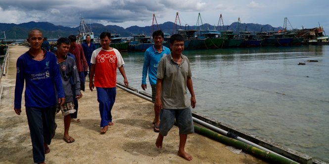 Một tốp ngư dân VN bị giữ ở cầu tàu đảo Tiga thuộc quần đảo Natuna, Indonesia. Phía sau là những con tàu cá của chính họ sắp bị đánh đắm - Ảnh: LÊ NAM