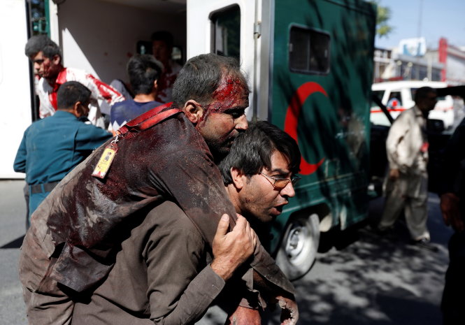 Cõng người bị thương vào bệnh viện vì số nạn nhân quá đông - Ảnh: Reuters