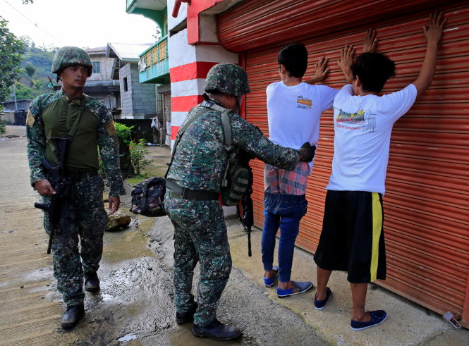 Binh sĩ khám xét thanh niên tại làng Sarimanok thuộc TP Marawi ngày 31-5 đề phòng là thành viên IS giả dạng - Ảnh: Reuters