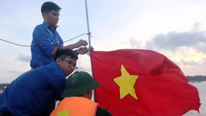 Các bạn sinh viên và đoàn viên treo cờ trên tàu cá của ngư dân - Ảnh: Vũ Thủy