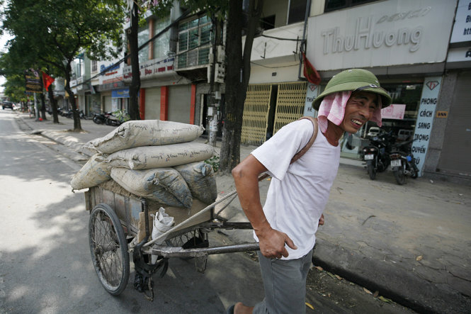 Người đàn ông này thì nhễ nhại mồ hôi với công việc kéo xi măng trên đường Đại Cồ Việt, Hà Nội - ẢNH: Nam Trần