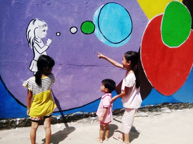 Các em nhỏ thích thú với bức tranh mới lạ ở hòn đảo của mình - Ảnh: Trần Mai