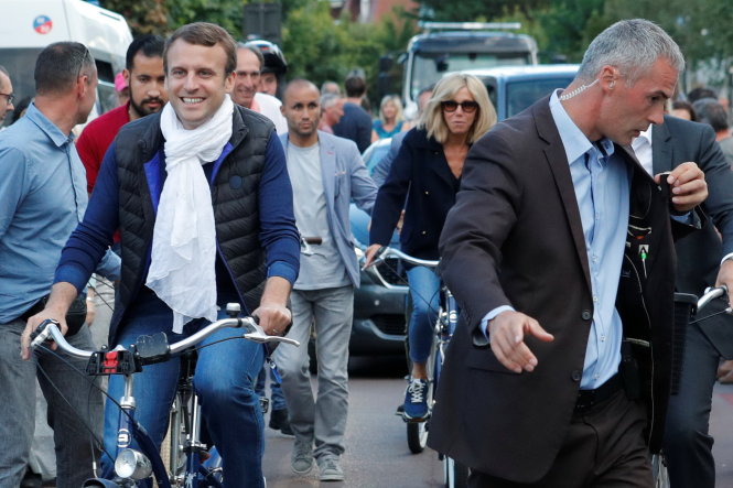Tổng thống Pháp Emmanuel Macron cùng phu nhân Brigitte Trogneux (giữa) đạp xe rời nhà riêng ngày 10-6 ở Le Touquet trong dịp về đây nghỉ cuối tuần và đi bỏ phiếu quốc hội - Ảnh: Reuters