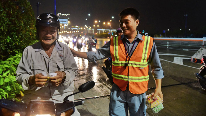 Người dân ai cũng vui vẻ khi nhận được áo mưa khi trú mưa tại miệng hầm sông Sài Gòn - Ảnh: HỮU THUẬN