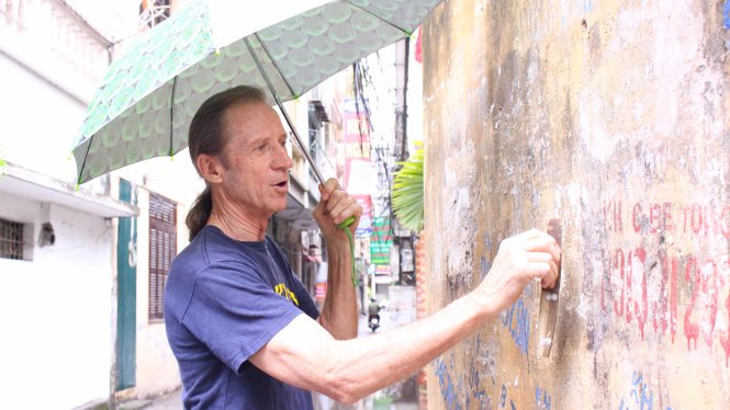 Ông Paul xóa một quảng cáo khoan cắt bêtông ở phố Nguyễn Ngọc Vũ - Ảnh: Hà Thanh