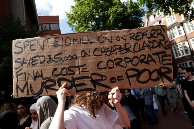 Một người dân giơ bảng phản đối đơn vị quản lý tòa nhà Grenfell trong cuộc tuần hành tại Kensington chiều 16-6 - Ảnh: Reuters