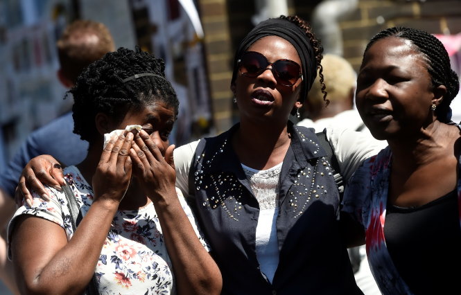 Những phụ nữ đến hát và cầu nguyện cho các nạn nhân gần hiện trường tòa nhà Grenfell không thể ngăn dòng nước mắt vào ngày 17-6 - Ảnh: Reuters