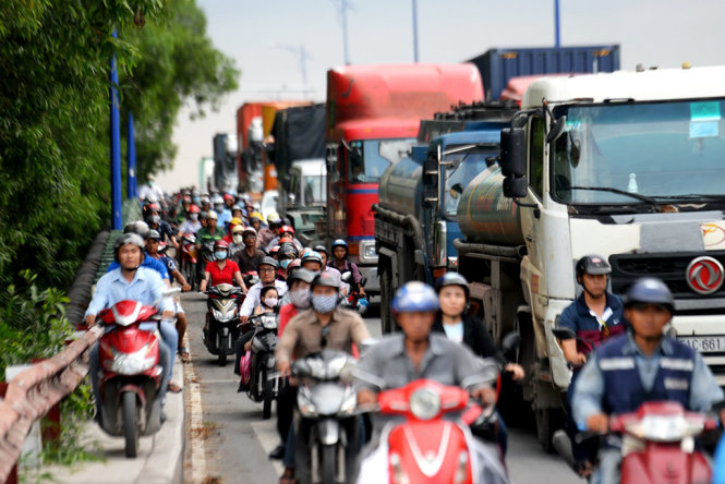 Xe tải và xe container xếp hàng dài qua cầu Giồng Ông Tố (hướng về cảng Cát Lái) gây khó khăn cho người đi xe máy qua khu vực này - Ảnh: HỮU KHOA