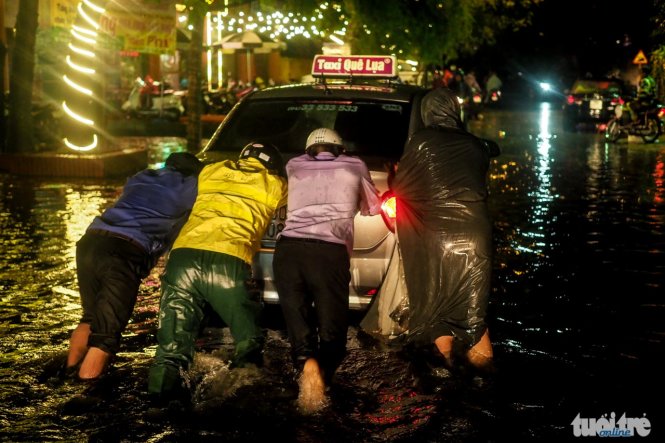 Một số người dân đang đẩy một chiếc xe thoát khỏi một khu vực bị ngập sâu, ảnh chụp tại dốc La Pho - Ảnh: Nguyễn Khánh