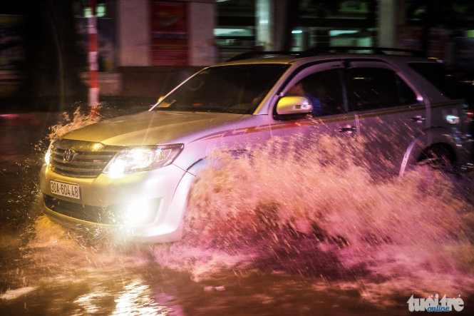 Một chiếc xe ô tô đang cố gắng thoát khỏi một tuyến đường bị ngập - Ảnh: Nguyễn Khánh