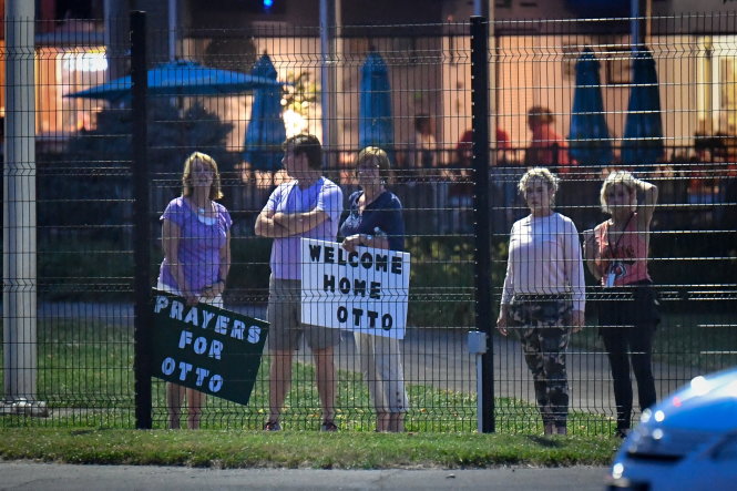 Người dân địa phương ở Mỹ đứng bên ngoài vòng rào phi trường Lunken ở Cincinnati ngày 13-6 chào đón sinh viên Otto trở về từ Triều Tiên trong tình trạng bị hôn mê - Ảnh: Reuters