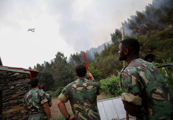 Binh sĩ theo dõi máy bay cứu hỏa vào cuộc - Ảnh: Reuters
