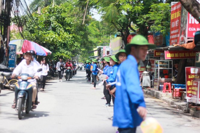 Sinh viên tình nguyện Hải Phòng đội nắng căng dây dài cả km trên đường Nguyễn Bình nhằm tránh ùn tắc giao thông - Ảnh: Tiến Thắng