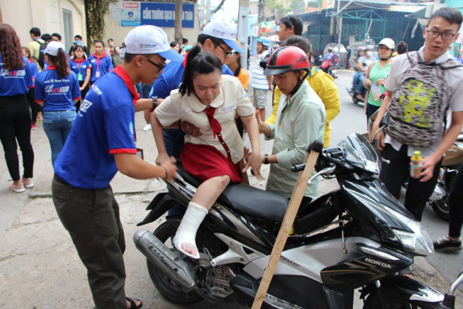 Bạn Nguyễn Phương Linh (lớp 12A10-14 trường THPT Hàn Thuyên) do bị gãy chân nên được đội tiếp sức mùa thi cõng từ phòng thi ra ngoài và hỗ trợ lên xe - Ảnh: Thu Trang
