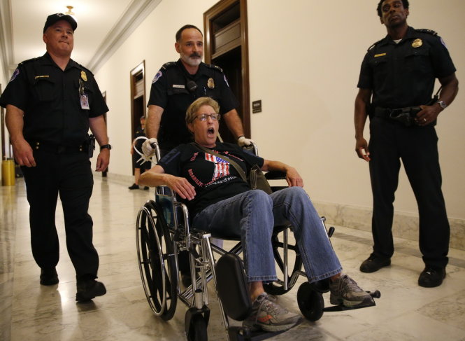 Cảnh sát áp giải một người phản đối dự luật chăm sóc sức khỏe mới bên ngoài văn phòng TNS Mitch McConnell ở Washington, ngày 22-6 - Ảnh: Reuters