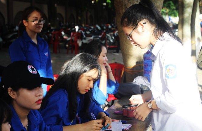 Các tình nguyện viên ở điểm thi Trường THPT Huỳnh Thúc Kháng, TP Vinh trông giữ đồ dùng cá nhân, điện thoại giúp thí sinh - Ảnh: Doãn Hòa