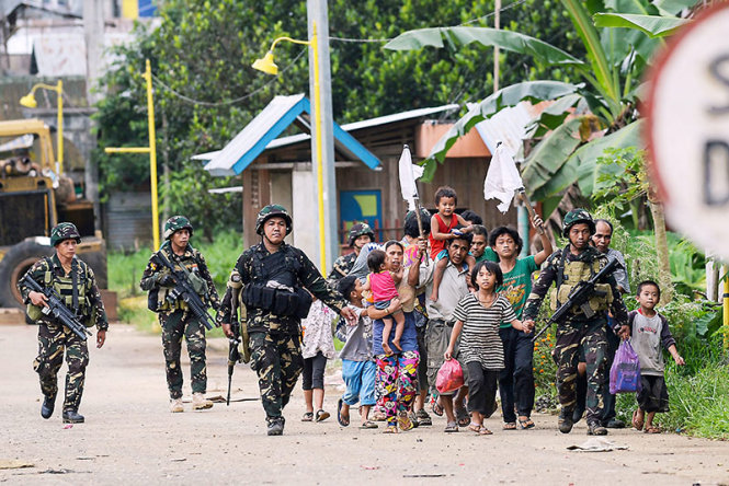 Các binh sĩ Philippines hộ tống một gia đình thoát khỏi Marawi - Ảnh: AFP