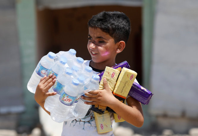 Niềm vui của một cậu bé Iraq khi được nhận nhu yếu phẩm chuẩn bị cho ngày lễ Eid al-Fitr ở Mosul - Ảnh: Reuters