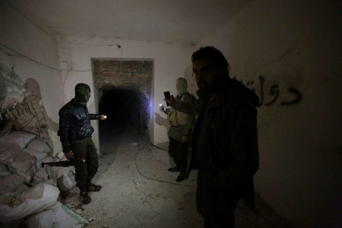 Các chiến binh thuộc lực lượng nổi dậy kiểm tra đường hầm IS từng sử dụng để kết nối hai tòa nhà trụ sở của chúng ở thành phố al-Bab phía bắc Syria - Ảnh: Reuters