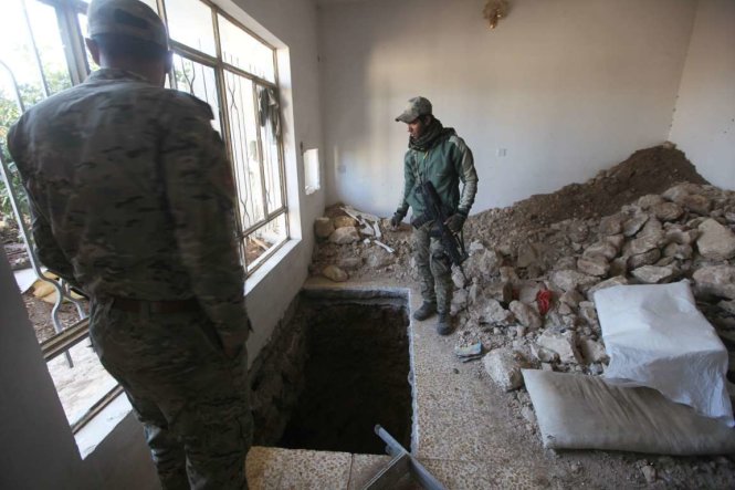 Lực lượng phản ứng nhanh của Iraq đứng bên một cửa hầm đào ngay trong một ngôi nhà ở vùng Albu Saif, phía nam thành phố Mosul - Ảnh: Reuters