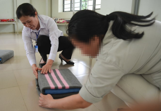 Quản giáo Nguyễn Thị Hương hướng dẫn học viên nữ cách gấp xếp chăn màn ngăn nắp - Ảnh: Tấn Lực