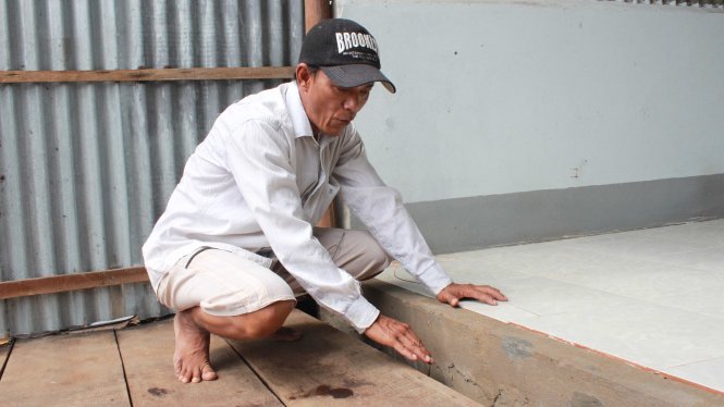 Ông Nguyễn Văn Hổ đang xem phần sụp lún giũa nhà trước và nhà sau của mình - Ảnh: Trần Nguyên