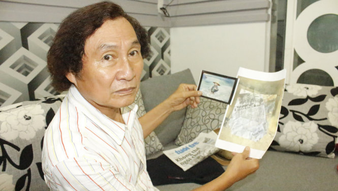 Họa sĩ Nguyễn Nhân bên ảnh chụp tranh và photocopy tờ báo có ảnh ông đã phóng tác - Ảnh Tiến Trình
