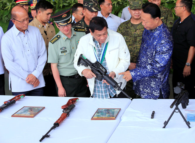 Ông Rodrigo Duterte thử một khẩu súng tại buổi trao quà của Trung Quốc tại căn cứ không quân Clark - Ảnh: Reuters