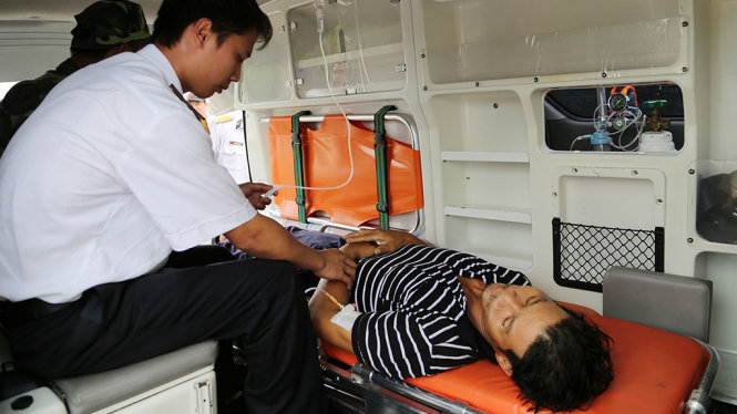 Các y  bác sĩ chăm sóc bệnh nhân Lê Văn Lại trên xe cứu thương về bệnh viện - Ảnh: QUANG TIẾN