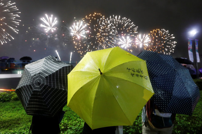 Người biểu tình cầm chiếc dù màu vàng, biểu tượng của cuộc biểu tình năm 2014, trước màn trình diễn pháo hoa kỉ niệm 20 năm Hong Kong được thu hồi về Trung Quốc tối 1-7 - Ảnh: Reuters