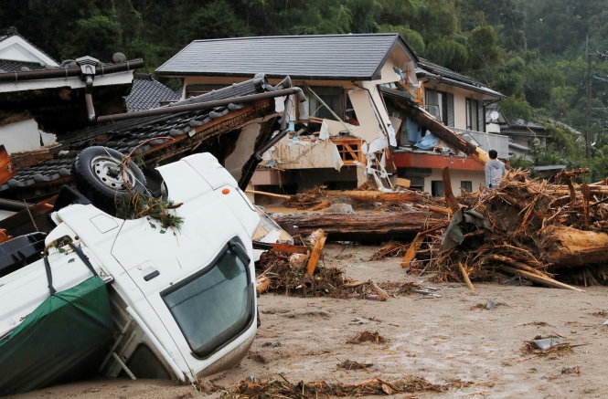 Xe lật nhào và nhà cửa hư hại vì mưa lớn và nước sông tràn bờ tại thành phố Asakura, tỉnh Fukuoka ngày 6-7 - Ảnh: Reuters/Kyodo