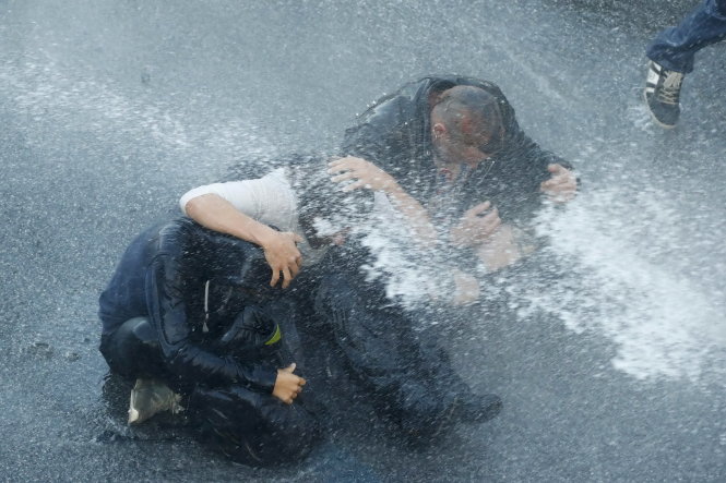 Người biểu tình dựa vào nhau chống vòi rồng của cảnh sát chống bạo động - Ảnh: Reuters
