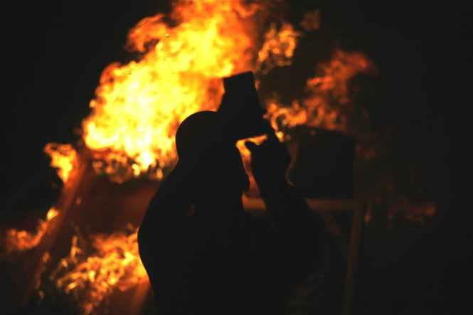Người biểu tình tranh thủ selfie bên đám lửa - Ảnh: Reuters