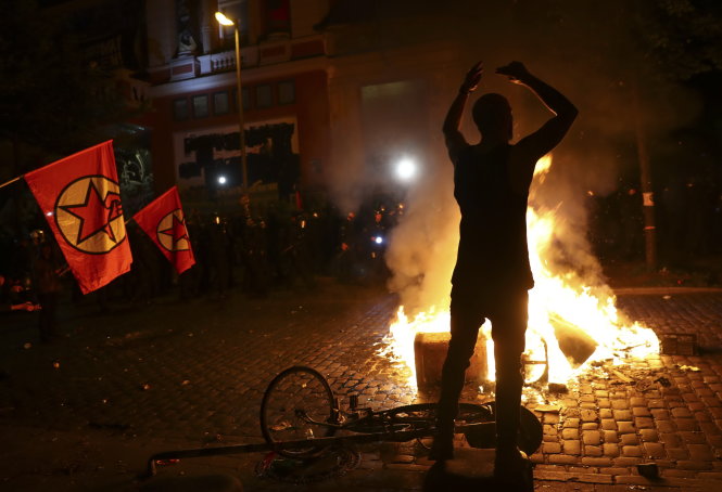Người biểu tình đương đầu với cảnh sát chống bạo động (góc trái) - Ảnh: Reuters