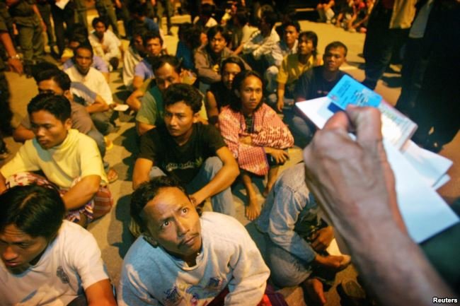 Lao động nhập cư người Indonesia bị bắt giữ ở ngoại ô thủ đô Kuala Lumpur của Malaysia và đang chờ nhân viên Cục Nhập cư Malaysia kiểm tra giấy tờ - Ảnh: Reuters