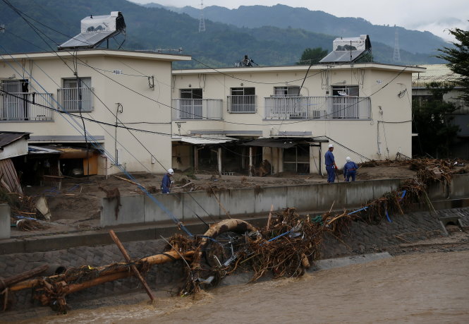 Lực lượng cứu hộ xem xét đường sá sạt lở do mưa lũ vào sáng 8-7 - Ảnh: Reuters