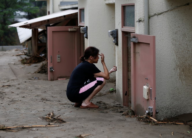 Một phụ nữ bần thần trước căn nhà bị bùn tràn đến phân nửa tầng trệt - Ảnh: Reuters
