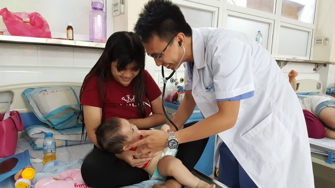 Bác sĩ Phạm Anh Tuấn dỗ dành để khám cho trẻ tại Bệnh viện Nhi T.Ư -
 Ảnh: Q.LIÊN