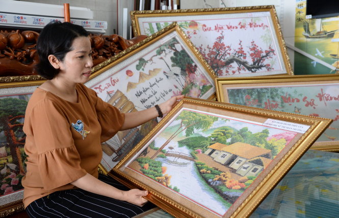 Chị Phạm Thị Mạnh và những bức tranh thêu mới được chuyển về từ Trường Sa - Ảnh: TỰ TRUNG