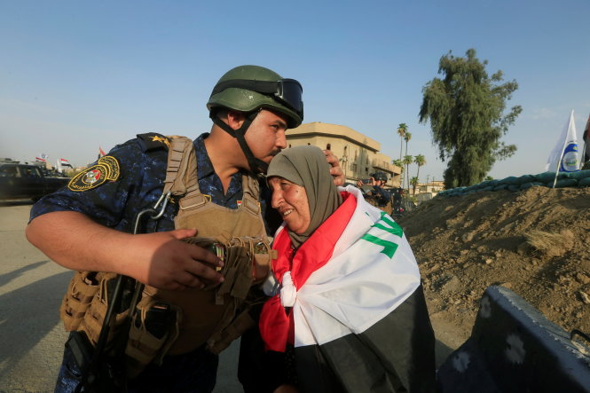 Một binh sĩ Iraq hôn người phụ nữ quấn cờ mừng chiến thắng ở Mosul - Ảnh: Reuters