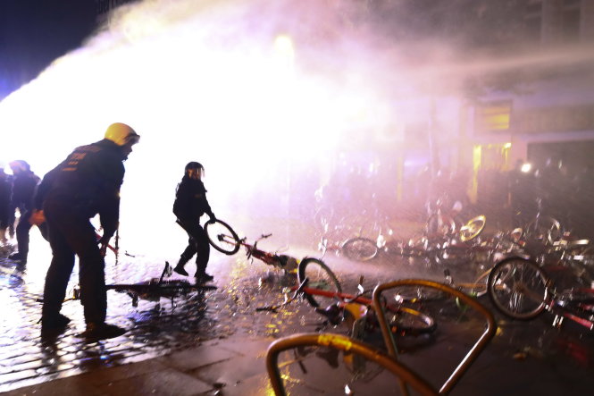 Cảnh sát chống bạo động phải dọn dẹp xe đạp do người biểu tình chất đống làm 