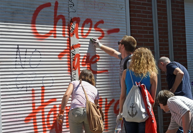 Người dân thành phố đi chùi rửa sơn xịt trên cửa - Ảnh: Reuters