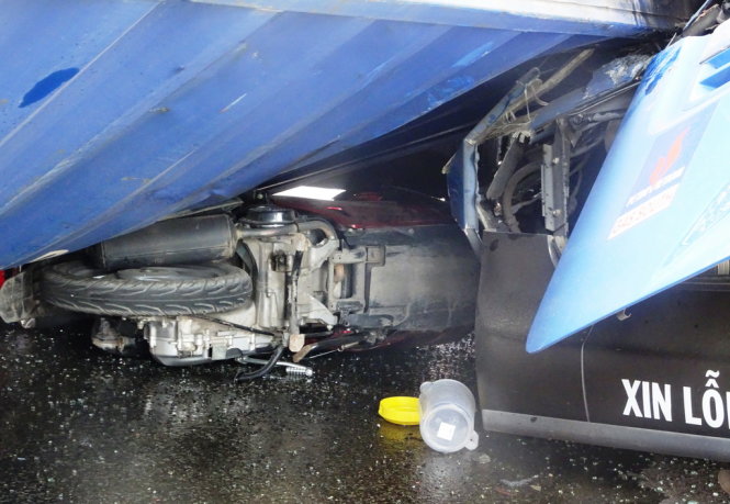 Một xe máy bị đè dưới thùng container sau tai nạn - Ảnh: Lê Phan